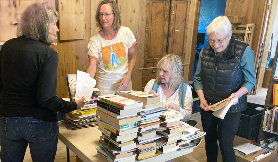 People standing at table choosing books to send to incarcerated people.