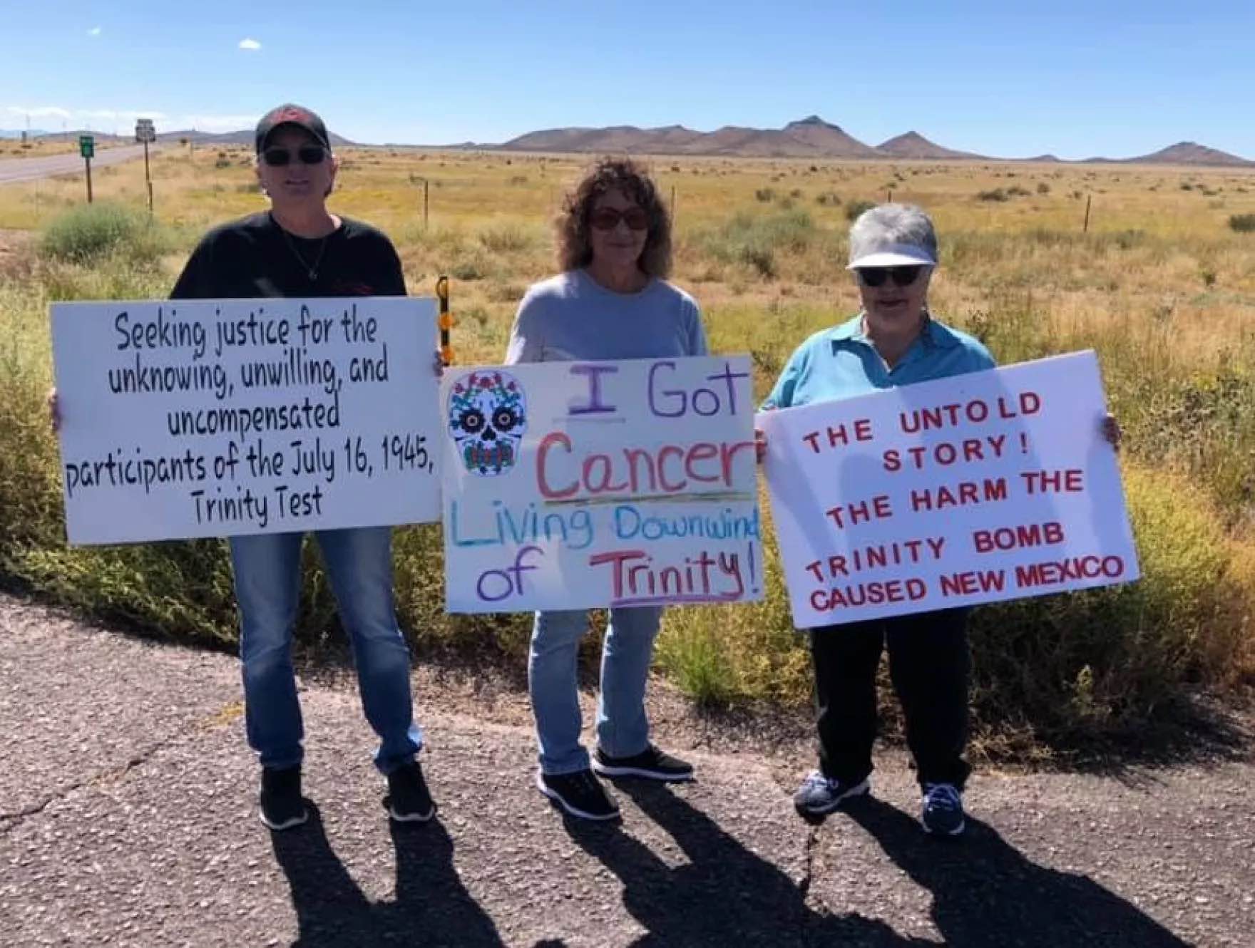 Three people holding signs talking about radiation exposure.