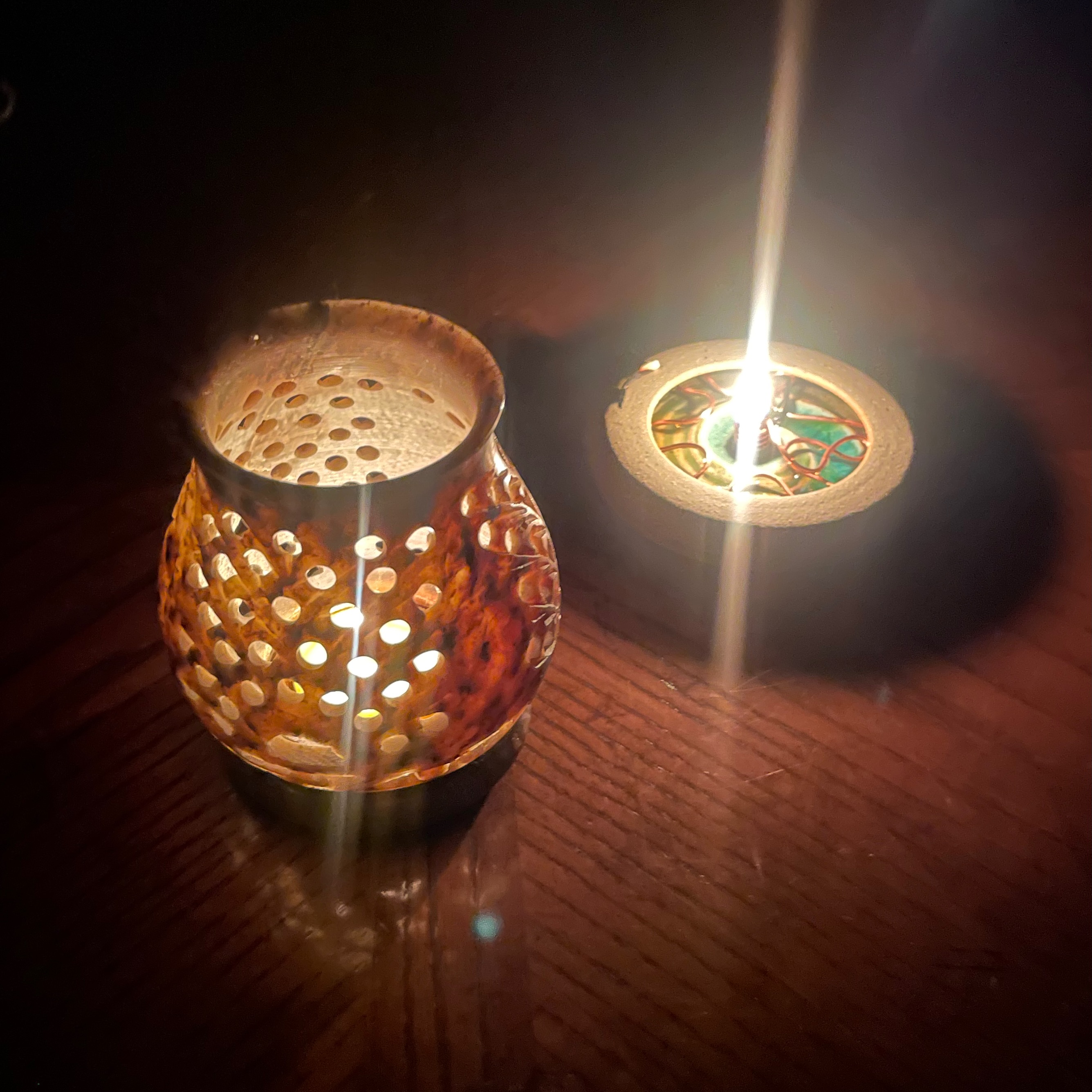 Two round candles flicker with light surrounded by dark